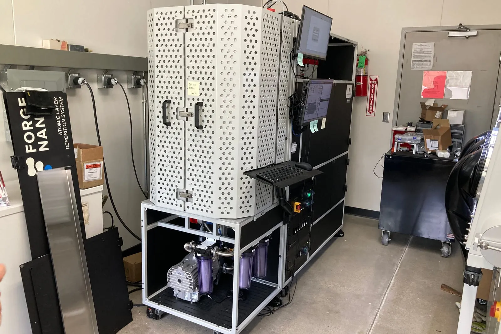 Forge Nano Prometheus fluidized-bed particle ALD reactor with its enclosure, vacuum system, and computer control station.